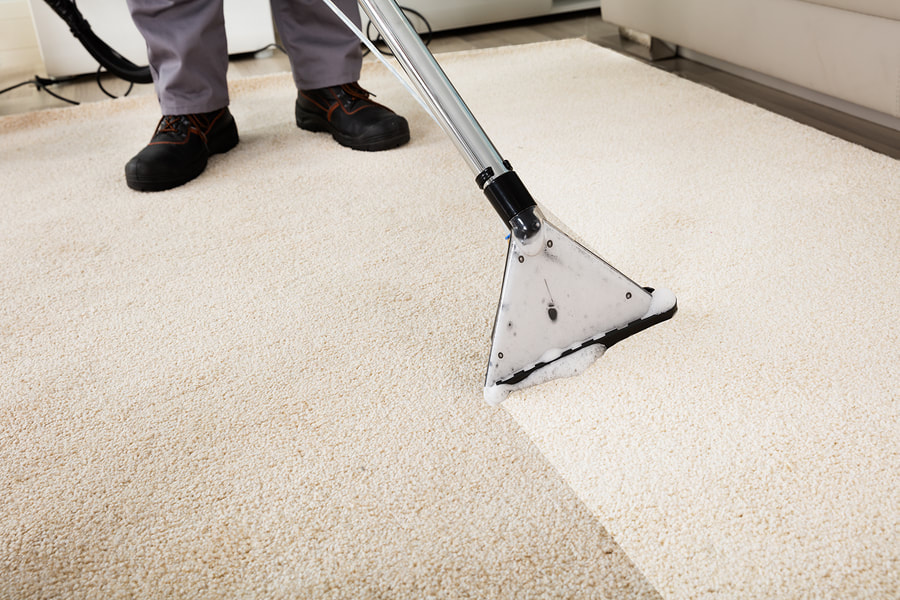 man cleans the carpet with a machine